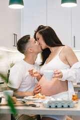 Pregnancy photo session at home, in the kitchen, in the room on the bed, by the window and in the bathroom, brushing your teeth, putting your hands on your tummy and making cheesecakes from flour