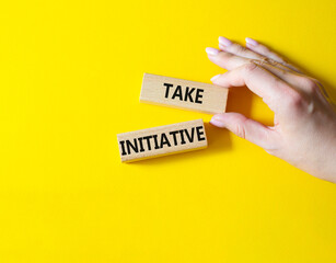 Take initiative symbol. Wooden blocks with words Take initiative. Businessman hand. Beautiful yellow background. Business and Take initiative concept. Copy space.
