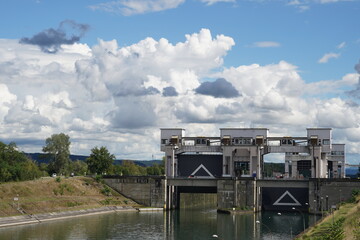 View on  two locks with open one gate situated next to hydroelectric power station Kembs on the river Rhine. On the both doors are white triangles. On sides are grass banks.