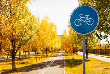 Round blue road sign Bicycle Path installed in park on an autumn sunny day