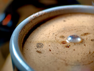 coffee milk foam, brown, in a black glass