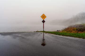 Road Ends sign in front of a lake on a foggy misty day