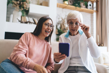 Positive aged multiethnic women watching video on smartphone