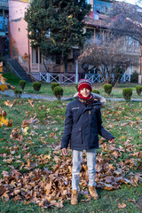 Boy throwing leaves up in autumn in Tbilisi Georgia