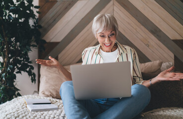 Thrilled elderly woman receiving good news on laptop