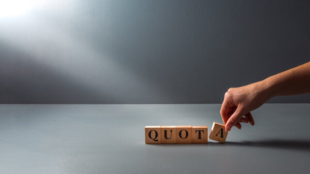 womans hand posing wooden block with the word quota . cocept of work Quota's .equality.