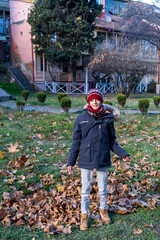 Boy throwing leaves up in autumn in Tbilisi Georgia