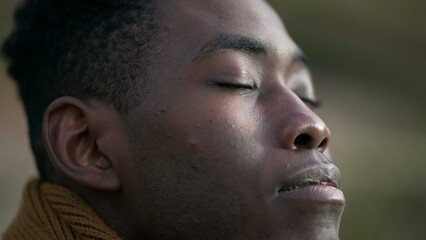 Obraz premium Contemplative young black man closing eyes in meditation