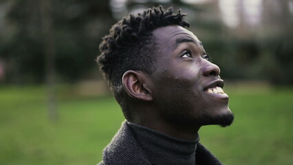 Contemplative young African black man standing looking at sky with HOPE and FAITH