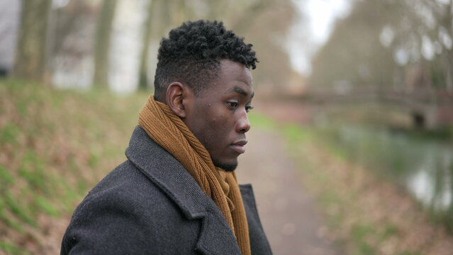 Contemplative young black man standing outside in nature park