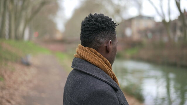 Contemplative young black man standing outside in nature park