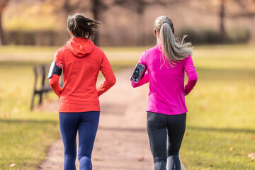 Back view of two female runners in an autumn park