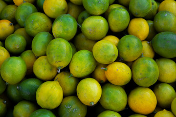 Background from citrus fruits. Yellow and green lemons in tray. Fruits in greengrocer's shop at a Georgian street market. The concept of buying farm products. Small business support. Vegan fruit. Food