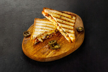 Fried grilled white bread club sandwich with jalapeno on wooden board.
