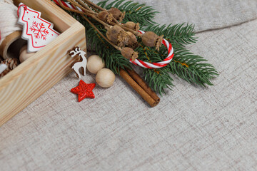  Christmas composition of wooden box with knitting balls, pine cones, wooden Christmas tree and deer, red lollipop and Christmas tree branch on gray background