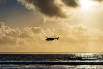 Hubschrauber, Helikopter im Tiefflug über dem Meer bei wolkenhimmel © JM Soedher