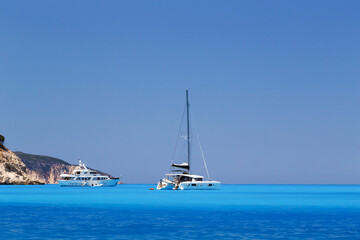 White yachts anchored in fantastic Myrtos Beach turquoise and blue bay. Summer scenery of famous and extremely popular travel destination in Cephalonia island, Greece, Europe.
