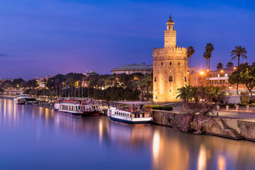 Naklejka premium Scenic view of Seville by night with Torre del Oro reflection in water