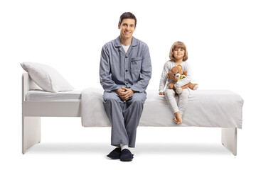 Father and daughter in pajamas sitting on a bed