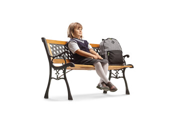 Schoolgirl with a backpack sitting on a bench and looking away