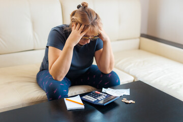 Worried and desperate caucasian woman calculating domestic money expenses doing paperwork and bank...