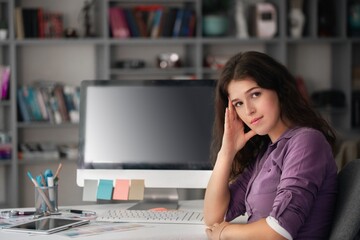 Young woman in office, studying or working on computer.