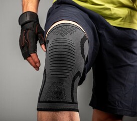 Athlete bodybuilder leg closeup, wearing knee support brace, elastic kneecap bandage, sleeve for...