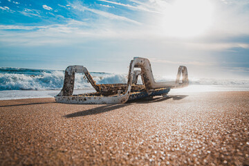 Washed up Plastic beach chair stuck in sand on shoreline during a beautiful day. Landscape Ocean...