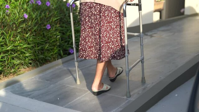 Asian senior woman patient walk with walker on ramp at home, healthy strong medical concept. 