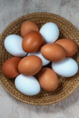 several fresh chicken eggs in a straw basket on a wooden background. Healthy eating concept.