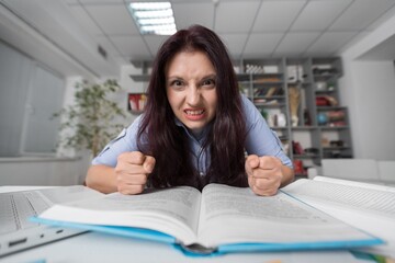 Young girl studying alone in library, in glasses with laptop.