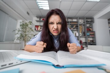 Young girl studying alone in library, in glasses with laptop.