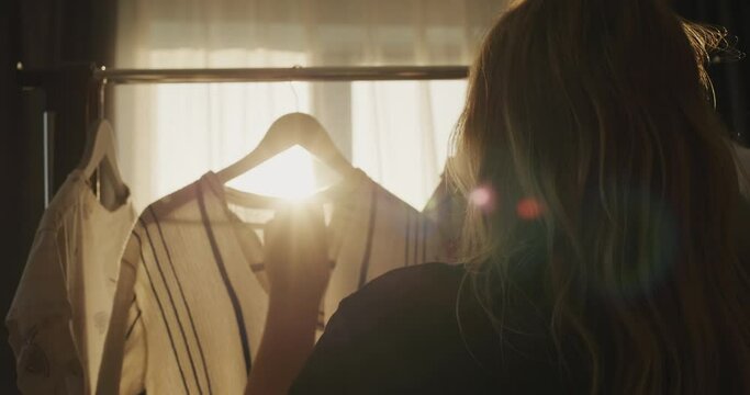 Silhouette of a woman choosing her clothes in the rays of the setting sun