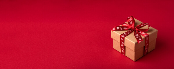 Christmas gift box with red bow on red background.