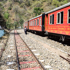 Fototapeta na wymiar Toy Train moving on mountain slopes, beautiful view, one side mountain, one side valley moving on railway to the hill, among green natural forest. Toy train from Kalka to Shimla in India, Indian Train