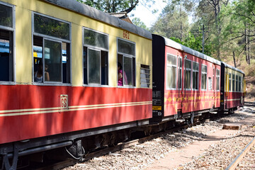 Obraz premium Toy Train moving on mountain slopes, beautiful view, one side mountain, one side valley moving on railway to the hill, among green natural forest. Toy train from Kalka to Shimla in India, Indian Train