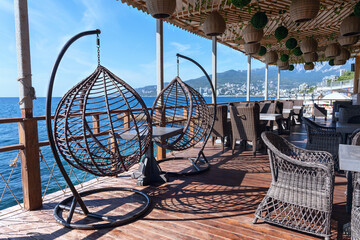 wicker willow chairs and wooden tables in a seaside cafe on the Black Sea coast