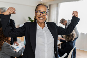 Close up of African american senior businesswoman with braided hair raising arms and clenched fists...