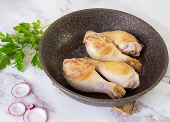 Fried chicken legs in a frying pan. Composition with spices and herbs. Side view