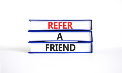 Refer a friend symbol. Concept words Refer a friend on books on a beautiful white table white background. Business and refer a friend concept. Copy space.