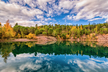 Scenic view of mirror like reflection of Carces lake in south of France in autumn colors against dramatic sky