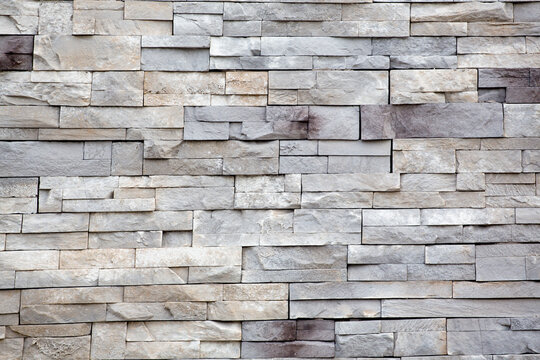 Rows of gray and white cut stone blocks for an exterior wall.