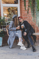 Young female best friends talking to each other discussing interesting themes during free time hipster girls joking and having fun together enjoying recreation with coffee to go on urban background