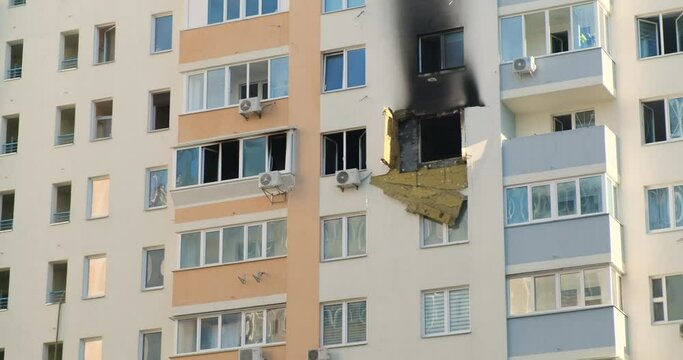 Black burnt window of an apartment in a high-rise building. Air conditioners hang on the walls. Yellow-blue building.