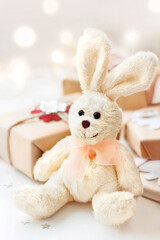 Wrapped presents with toy plush rabbit, symbol of 2023 New Year. Decorations for Christmas tree on festive background. Holiday greeting card.