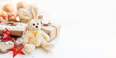 Wrapped presents with toy plush rabbit, symbol of 2023 New Year. Decorations for Christmas tree. Holiday background with copy space.