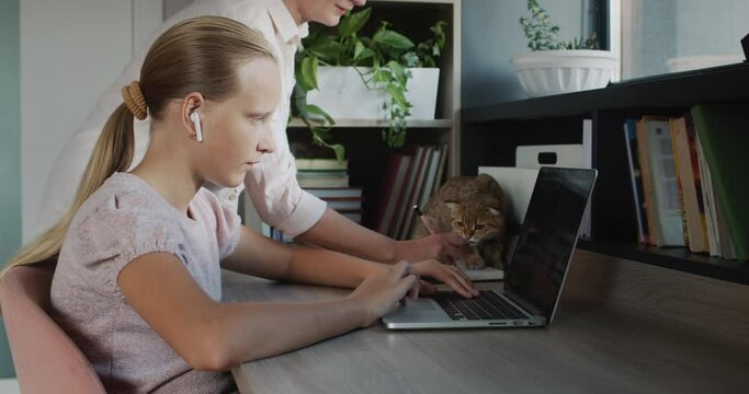 Woman helps a teenage girl do her homework. Education at home concept