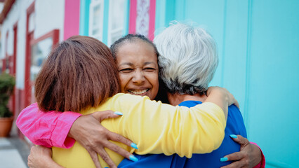 Happy diverse senior people hugging each other outdoor - Older friends community concept - Focus on...