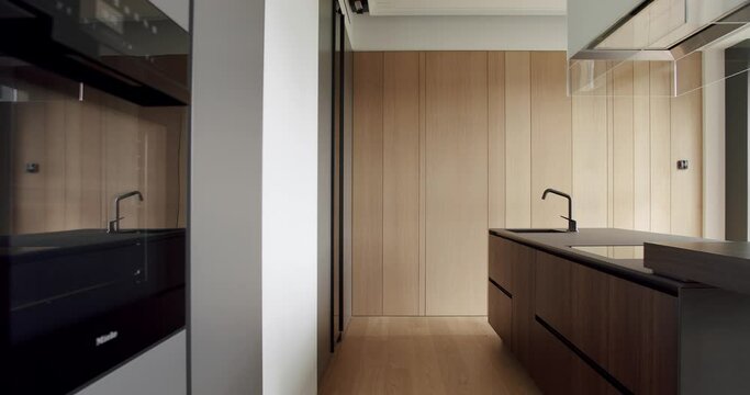 Beautiful kitchen interior with new stylish furniture. Real Luxury kitchen with an island. Stylish interior of the Kitchen. Minimalist kitchen room in white colors with dining area of natural wood