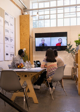 Business people video conferencing with colleagues on screen
